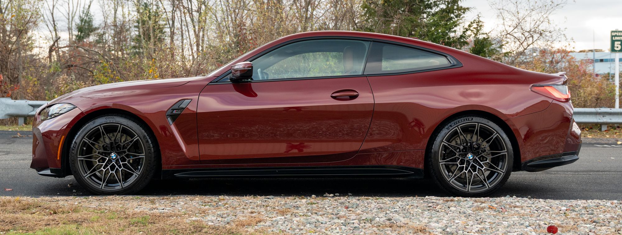 A red BMW M4 parked side on outdoors under an overcast sky