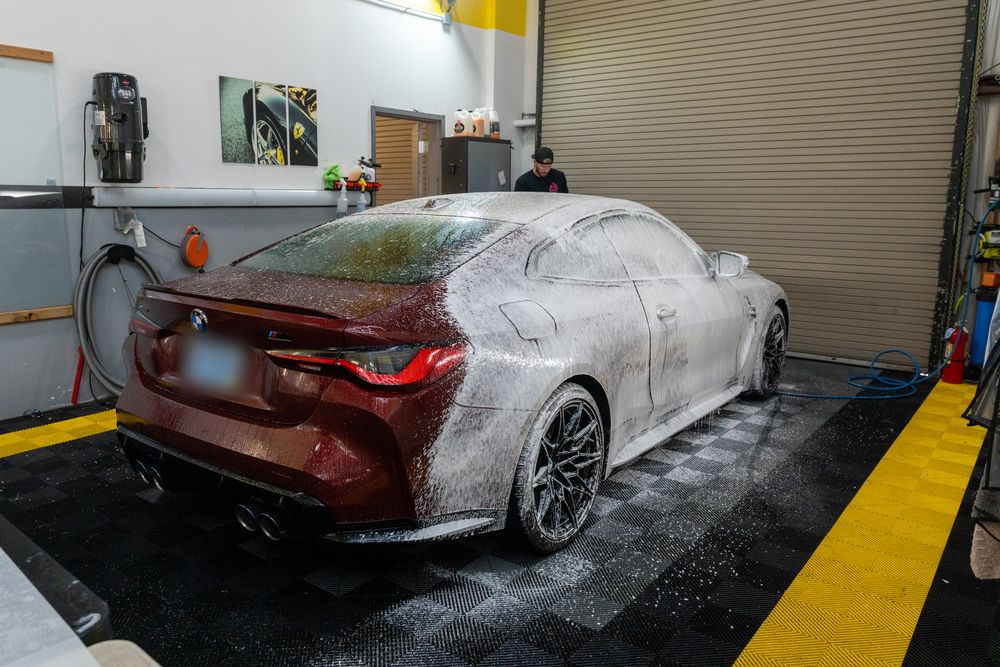 A red BMW M4 covered in wash foam in the ACP bay
