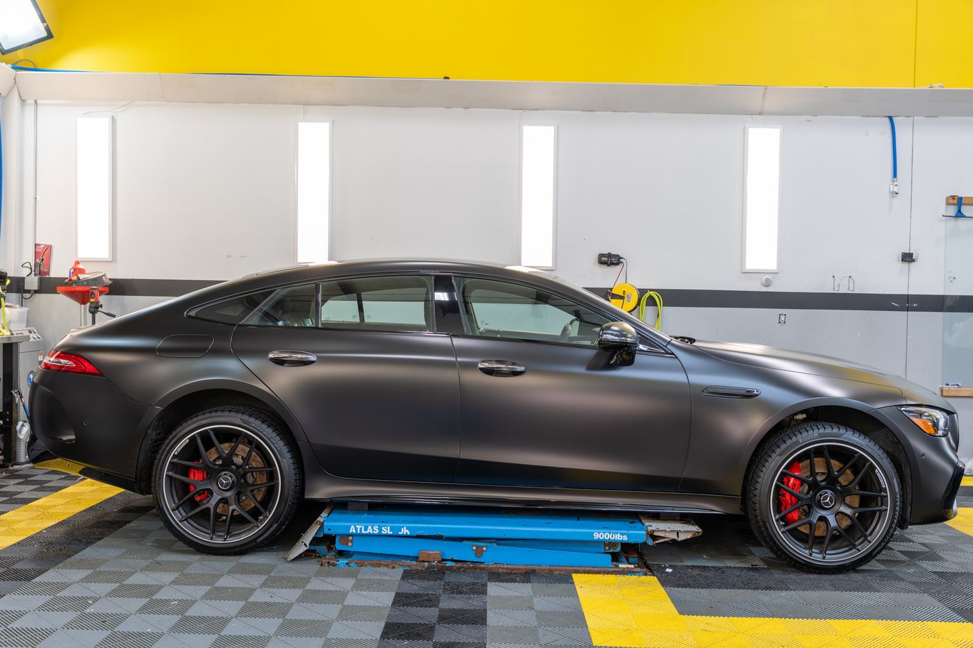 A satin black Mercedes-AMG GT 63 in the ACP bay, yellow wall behind