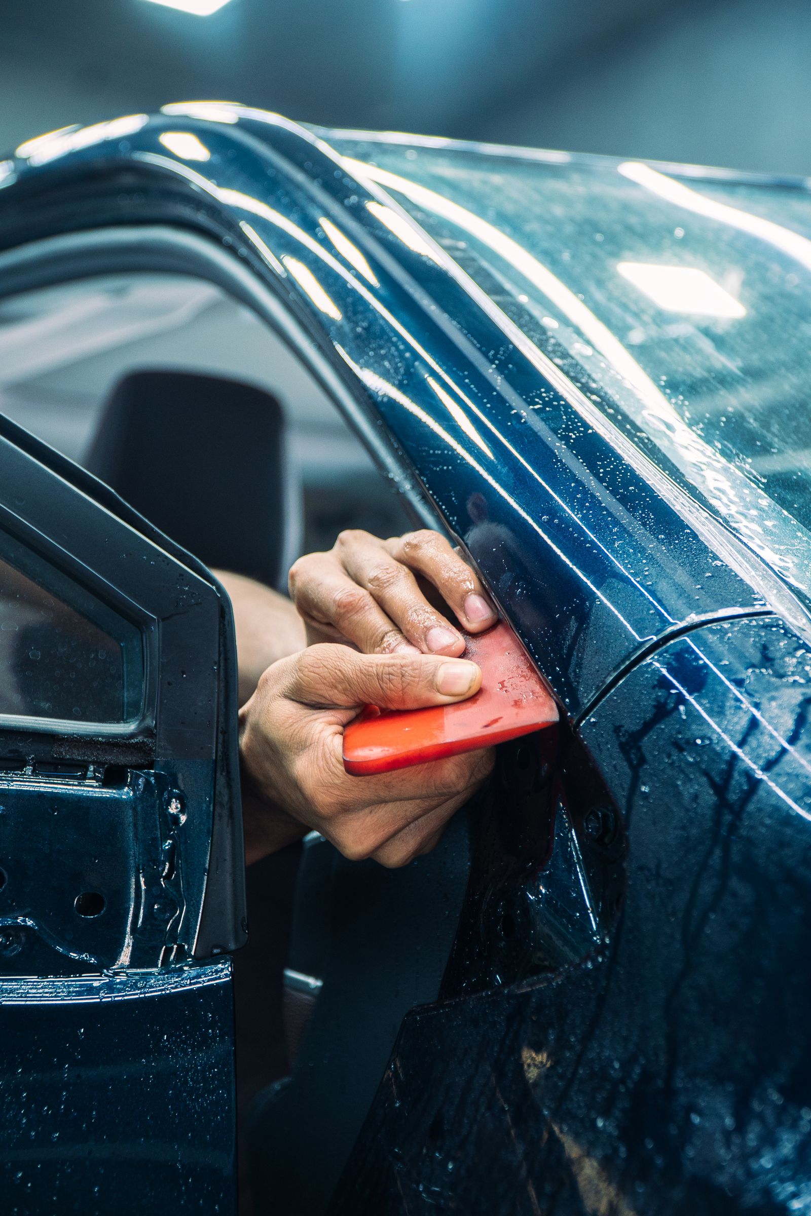 A technician fitting paint protection film to a car door