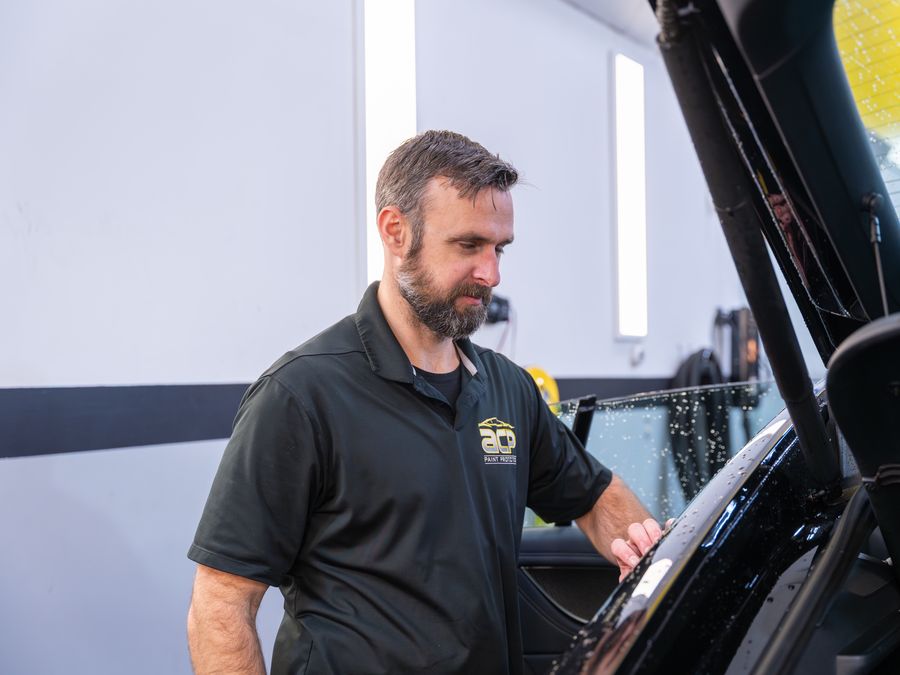 An ACP technician inspecting a black car before film goes on