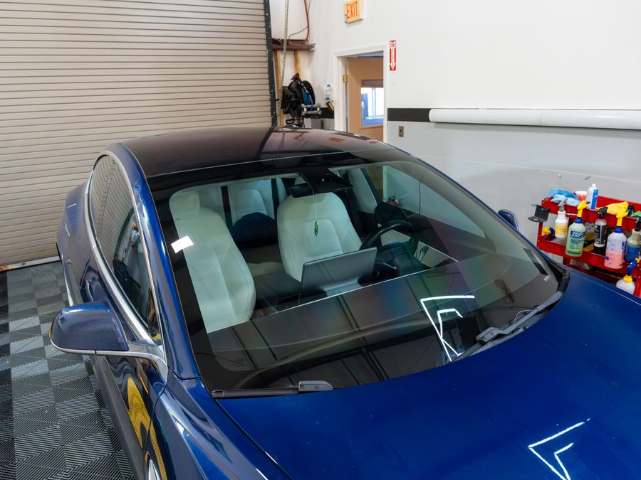 A blue Tesla Model 3's windshield and camera housing in the ACP bay